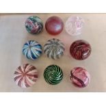 Nine coloured glass paperweights.