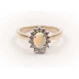 A hallmarked 9ct yellow gold opal and diamond cluster ring, set with an oval opal cabochon