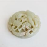 A pale green jade round pierced disk with spiral dragon. Approx 5cm.