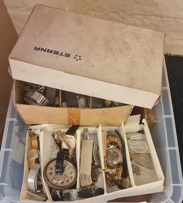 A box of watch parts and wrist watches.