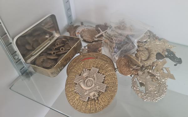 A collection of military cap badges and buttons.