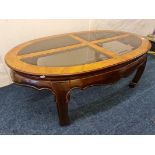 A walnut oval coffee table with glass top