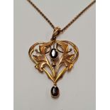 An Edwardian garnet dropper pendant, the open metalwork foliage scroll design set with a central