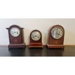 Three arched top mantle clocks one with inlay urn to front.