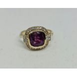 A pink sapphire and diamond ring, set with a cushion cut pink sapphire, measuring approx. 8x8mm