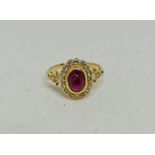 A ruby and diamond ring, set with a central oval ruby cabochon, surrounded by a border of round