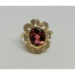 A pink tourmaline and diamond ring, set with a central oval pink tourmaline cabochon, measuring