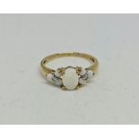 A hallmarked 9ct yellow gold opal and diamond ring, set with a central oval opal cabochon, flanked