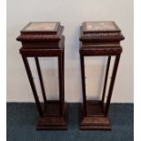 A pair of mahogany finished marble topped plant stands with glass shelves.