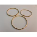 Three baby bangles, of differing designs, two stamped with Arabic numerals, the other hallmarked 9ct