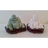Two carved stone Buddhas on wooden bases.