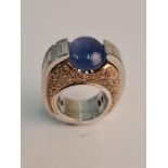An American style stamped 17383 750 ring,central blue stone flanked by baguette diamonds either side