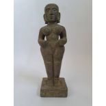 A hand carved stone nude female statue with faded symbols to base. 40 cm.