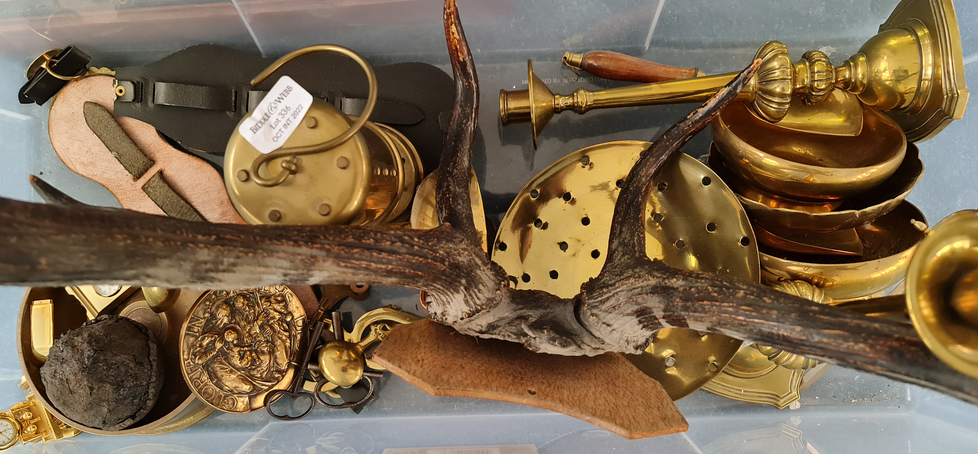 A collection of brass items candlesticks shell ashtray cannonball and a set of deer’s antlers.