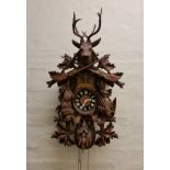 A Black Forest cuckoo clock carved with hunters design Swiss musical movement.