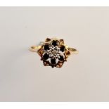 A 9ct gold ring set with a diamond and 6 sapphires in floral set.