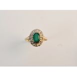 A 9ct good ring set with central emerald stone surrounded by 16 diamond chips.