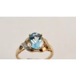 A 9ct gold ring set with pale blue stone and and stones to shoulders.