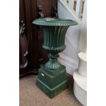 A green painted cast iron garden urn on square base height 68 cm.