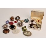A collection of various gem set brooches, circular patterned brooches and a green wedgwood design