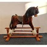 A MJ Mark brown rocking horse on wooden base.