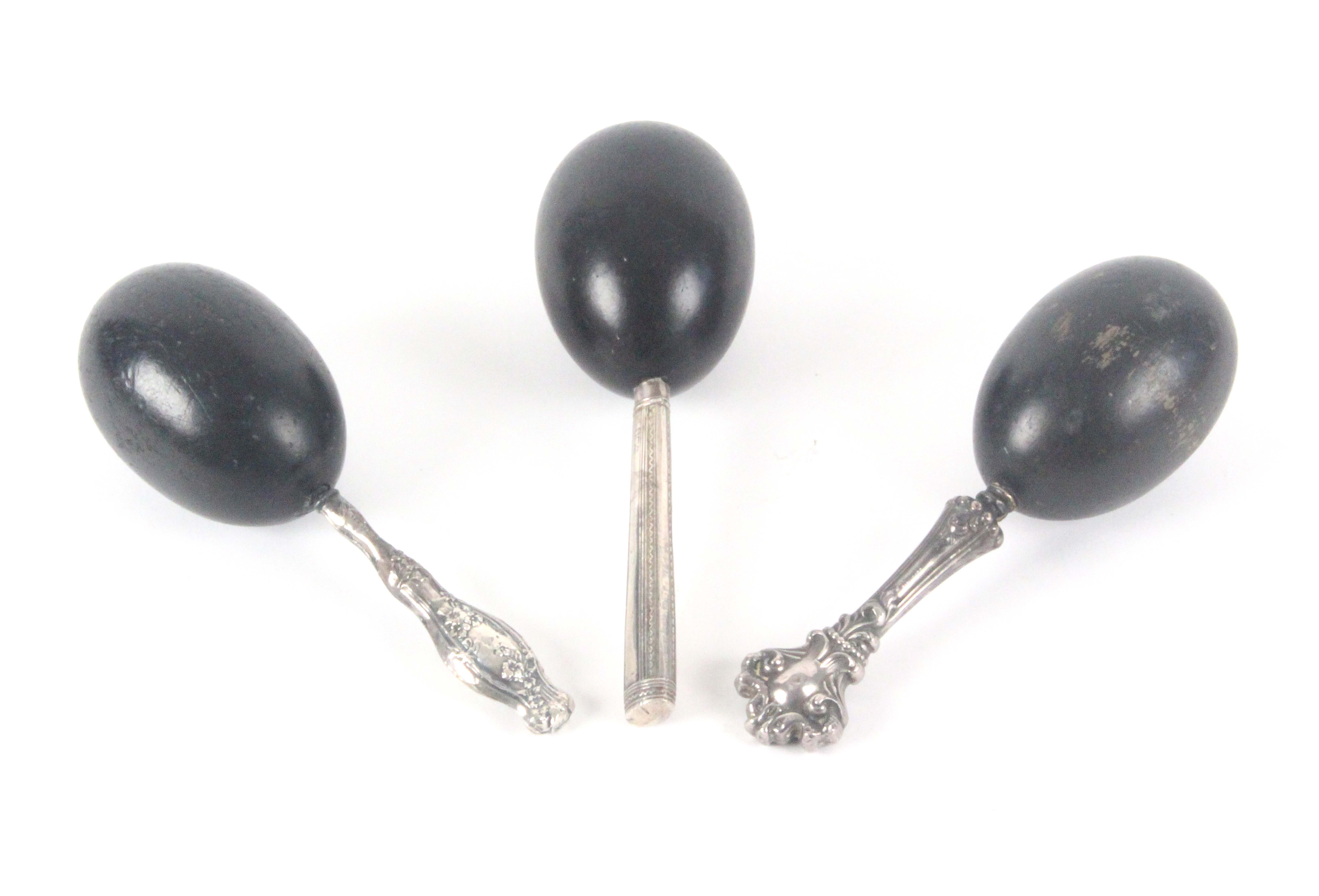 Three ebony egg form darners, two with decorative white metal handles stamped 'sterling', and