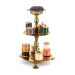 A brass reel stand, the circular base raised on three pad feet to a baluster turned stem and