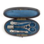 A five piece silver sewing etui, circa 1860, the ebonised oval case edged in brass with a lid plaque