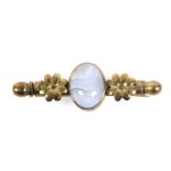 A brass nanny brooch, centred by an oval polished agate flanked by flower heads, complete with