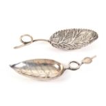 Two leaf bowl silver caddy spoons, comprising an engraved bowl example to curled handle mounted with