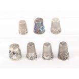 Seven white metal continental thimbles, five with decorative friezes, one with pierced sides and