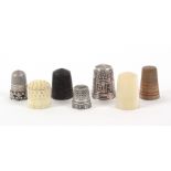 Seven various thimbles, comprising a mother of pearl example, a bone example, a rosewood example, an