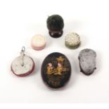 Four pin cushions and two emeries, comprising an oval papier mache pin cushion, one side in