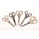 Five pairs of silver mounted scissors, with steel blades, three pairs with curved blades, largest