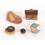 Five pin cushions, comprising a jockey cap in alternate silks divided by pins, 6.7cms, a geometric