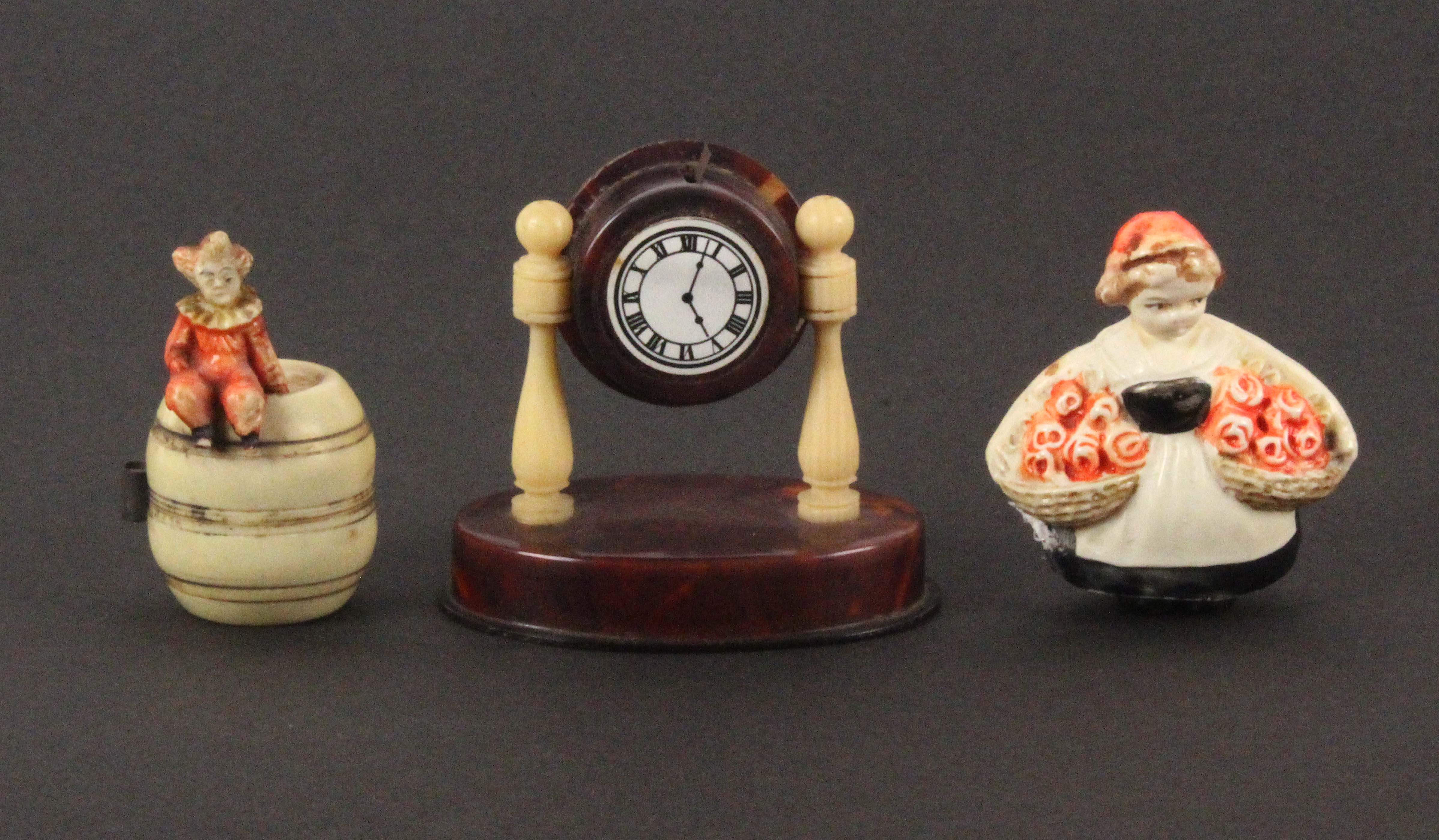 Three novelty celluloid tape measures, comprising a mantel clock, replacement plain brass tape,