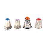 Four continental white metal thimbles, all with stone tops, one with robust flower head frieze