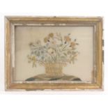 A late 18th Century embroidered silk panel of a basket of flowers, on a grassy mound, staining to