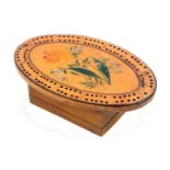 An early Tunbridge ware white wood painted and inlaid oval cribbage board, the centre painted with a