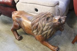 A large carved wooden sculpture of a lion, approx. 104cm length, 60cm height