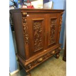 A Continental carved oak two door cabinet and stand, 123cm wide