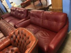 A red leather three seater settee and a two seater settee