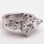 A platinum three stone diamond ring, the central marquise brilliant cut diamond, colour F-G, clarity