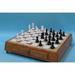 A Onyx chess board set in an oak frame, with carved wood chess pieces