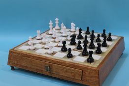 A Onyx chess board set in an oak frame, with carved wood chess pieces