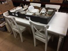 A modern white dining table and four chairs