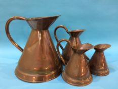 A set of four graduated copper jugs