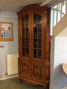 A reproduction mahogany carved corner cabinet