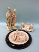 A Continental porcelain inkwell, a framed bisque circular plaque and a figure group (3)