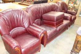 A purple leather three piece suite and foot stool